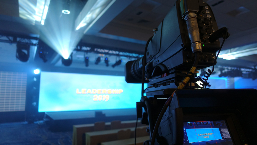 Professional video camera with a long lens designed for capturing a corporate event, fog creates dramatic lighting effects