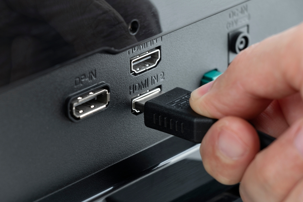 Hand-inserting an HDMI cable into a monitor, a vital step with cables from your audio visual equipment supplier.